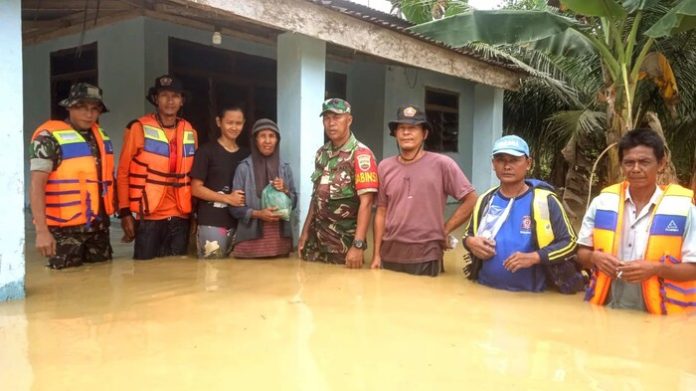 Sejumlah petugas memberikan bantuan bahan makanan kepada warga terdampak banjir yang bertahan di rumahnya (f:ist/mistar)