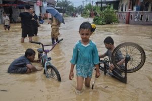 Anak-anak bermain ria di tengah banjir setelah hujan deras yang menyebabkan sungai meluap dan melanda Kelurahan Sitirejo III, Medan Amplas, Medan, Sumatera Utara Rabu (27/11/024)