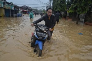 Warga mendorong sepeda motornya saat melintasi banjir di Jalan Selamat, Medan Amplas(f:adil/mistar)