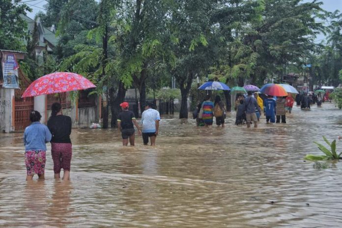 Warga Kelurahan Sitirejo III berjalan melintasi banjir di Jalan Selamat, Medan Amplas untuk mencari tempat pengungsian yang aman (f:adil/mistar)