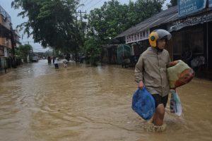 Warga mengamankan barang berharga saat melintasi banjir di Jalan Selamat, Medan Amplas. (f:adil/mistar)