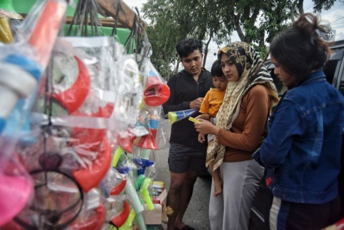 Pedagang terompet musiman melayani pembeli di Jalan Sisingamangaraja, Medan, Selasa (31/12/24). Menjelang malam pergantian tahun 2024-2025, penjual terompet musiman mulai marak di depan Taman Makam Pahlawan dengan variasi terompet yang dijual dengan harga Rp10 ribu - Rp 35 ribu. Menurut pedagang, omzet penjualan terompet tahun ini menurun dibanding tahun sebelumnya.