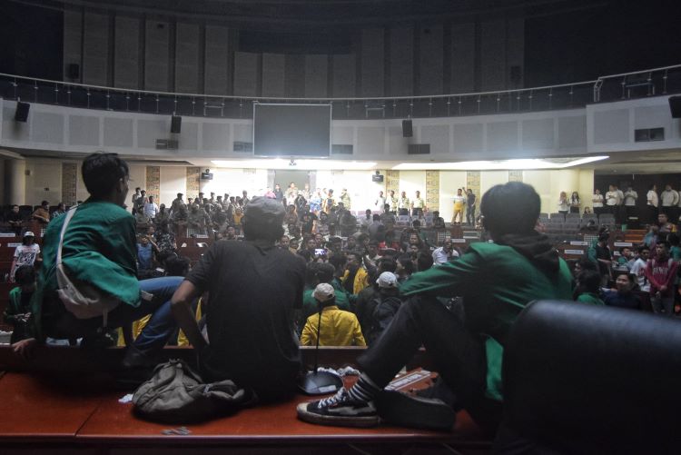 Mahasiswa tengah duduk di kursi pimpinan dewan saat berunjuk rasa di dalam Gedung Ruang Rapat Paripurna DPRD Sumut, Medan, Senin (30/12/24).