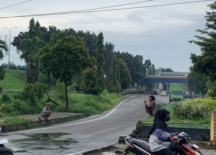 Dua pria berkedok Pak Ogah masih terlihat di persimpangan pintu tol Bandar Selamat