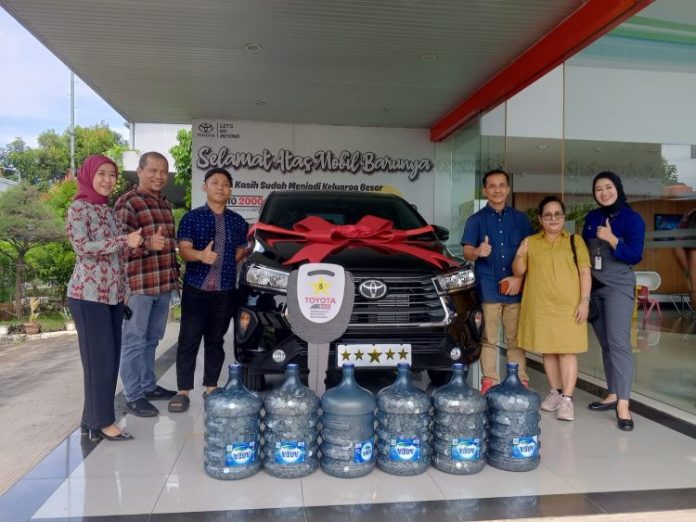 Renta (dress kuning) bersama suami membeli mobil dengan tabungan uang receh saat dijumpai wartawan di dealer mobil.