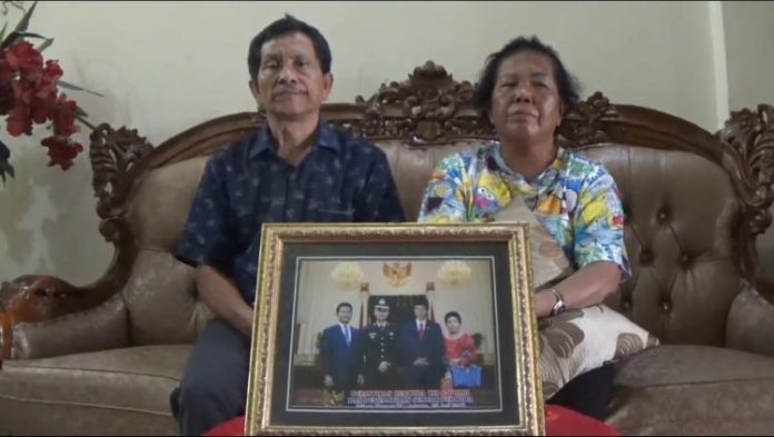 Orang tua Tomi memperlihatkan foto anak mereka saat dilantik Presiden Joko Widodo.