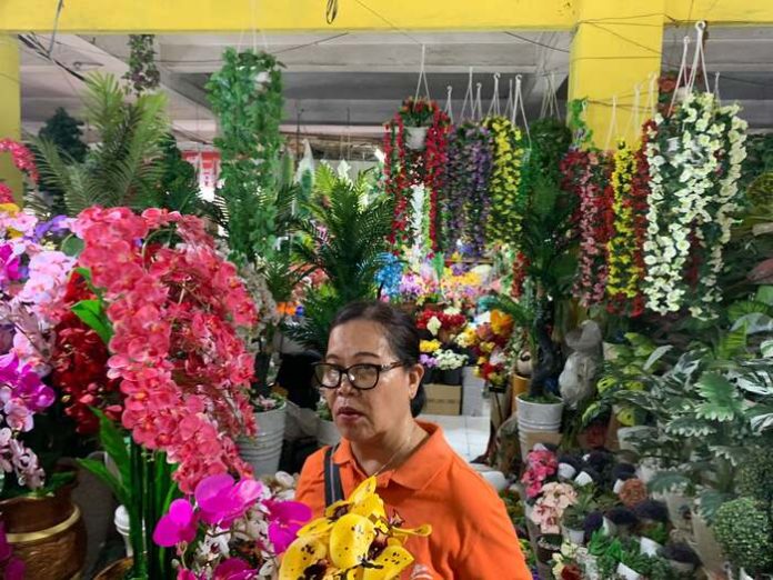 Gina, pedagang bunga artificial di Pusat Pasar Medan sedang memberikan contoh dagangannya (f:ari/mistar)